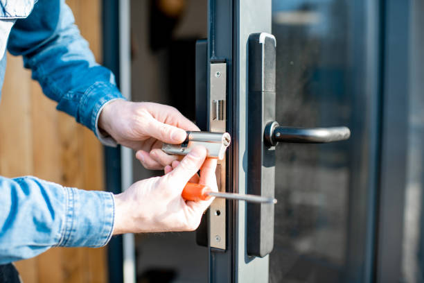 Locksmith fitting a lock cylinder into a metal door frame