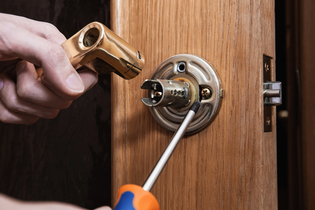 Locksmith installing a brass handle and lock cylinder on a wooden door