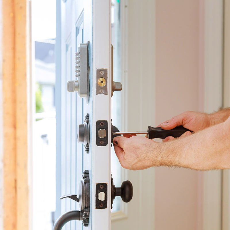Screwdriver adjusting door lock hardware on a white door